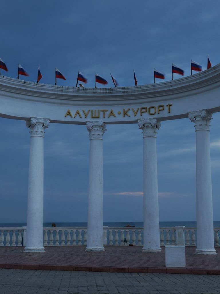Белая колоннада-ротонда «Алушта-курорт» на набережной вечером