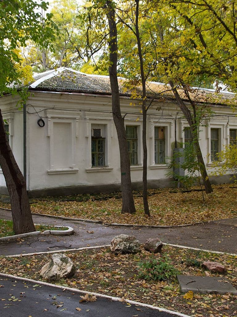 Старое здание и дорожки в тени деревьев курортного парка Саки