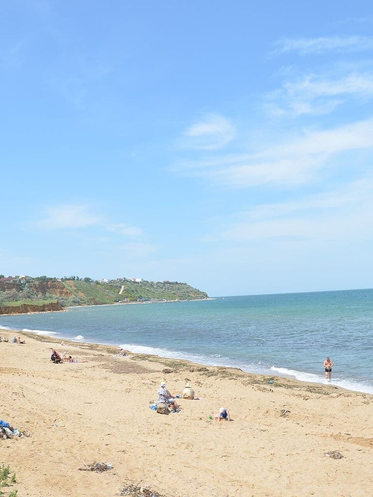 Песчаный пляж Учкуевки, море и зелёный берег вдали